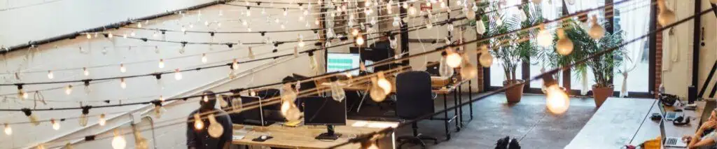 Moderne kantoorruimte met creatieve werkplekken en sfeervolle verlichting.