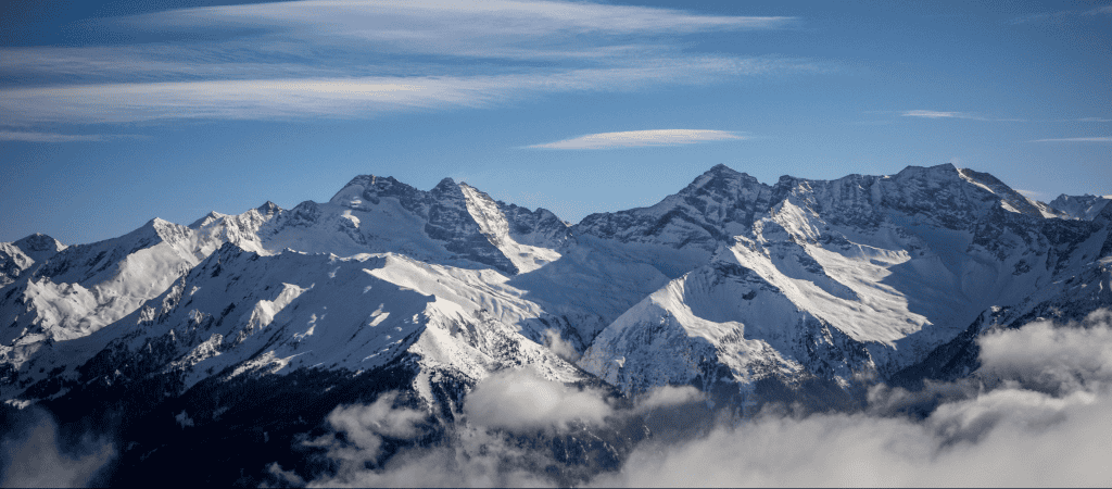 Adembenemende sneeuwbedekte bergen in de Alpen met blauwe lucht en wolken.